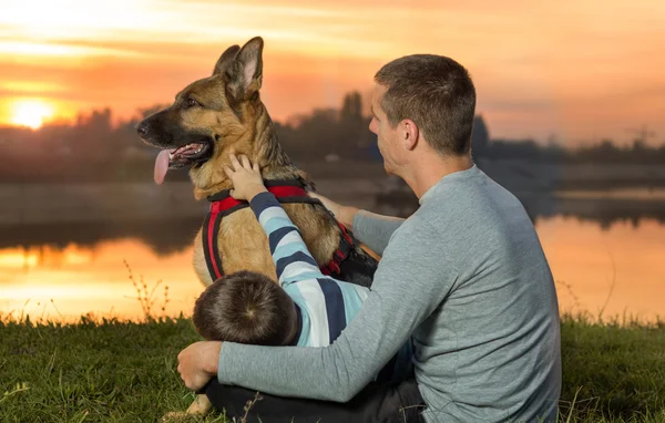 Vader en zoon en Duitse herder in de natuur kijken naar de zonsondergang — Stockfoto