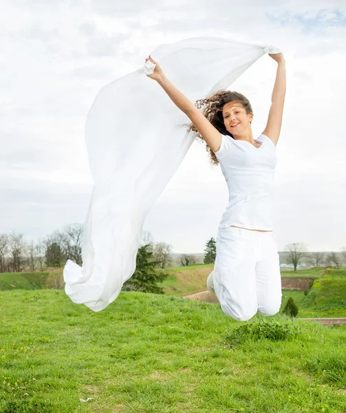 Young happy woman jumps and holding a white piece of cloth in th — Stock Photo, Image