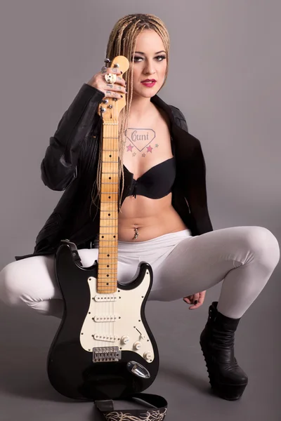 Девушка с татуировками, позирующая с гитарой — стоковое фото