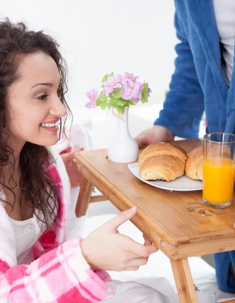 Beautiful young woman surprised by partner bringing breakfast in — Stock Photo, Image