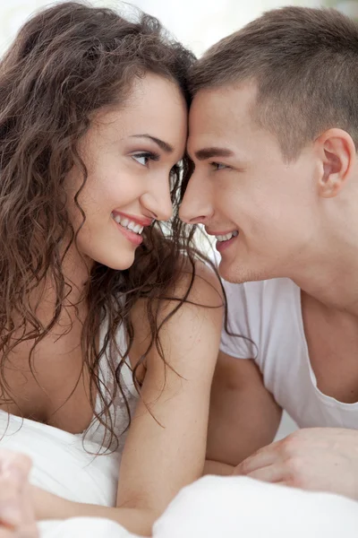 Happy couple lying on bed looking at each other Stock Photo