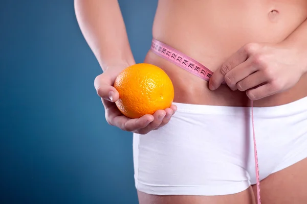 Beauty female body with measuring tape and orange — Stock Photo, Image