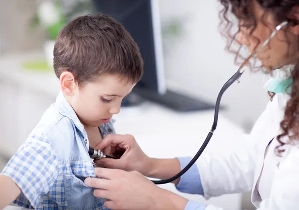 Jovem médico amigável examinando um menino — Fotografia de Stock