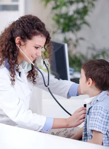 Jeune femme souriante médecin amical examinant un petit garçon — Photo