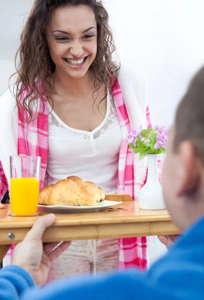 Beautiful young woman surprised by partner bringing breakfast in — Stock Photo, Image