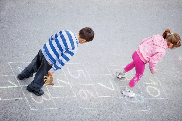 Brother and sister play hopscotch — Stock Photo, Image