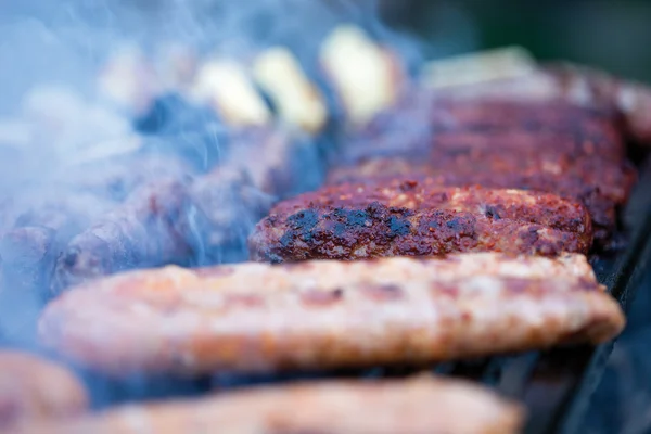 Salsicce di maiale e manzo che cuociono sui carboni ardenti su un barbecue — Foto Stock