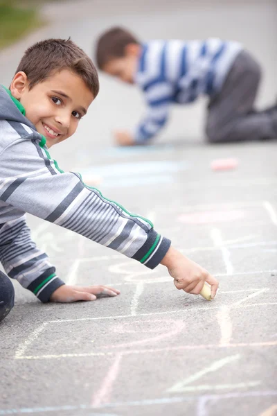 Schattige kleine jongen tekenen met krijt buitenshuis — Stockfoto