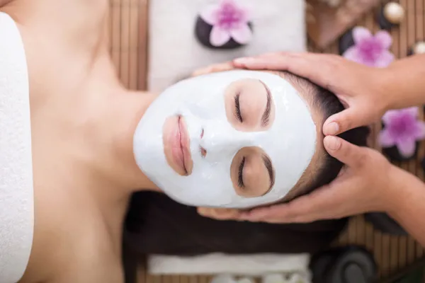 Terapia de spa para mulher jovem com máscara facial no salão de beleza — Fotografia de Stock