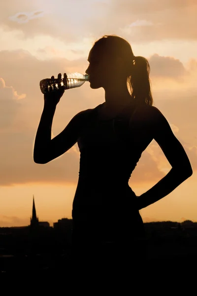 若い陽気な女性の飲料水のシルエット — ストック写真