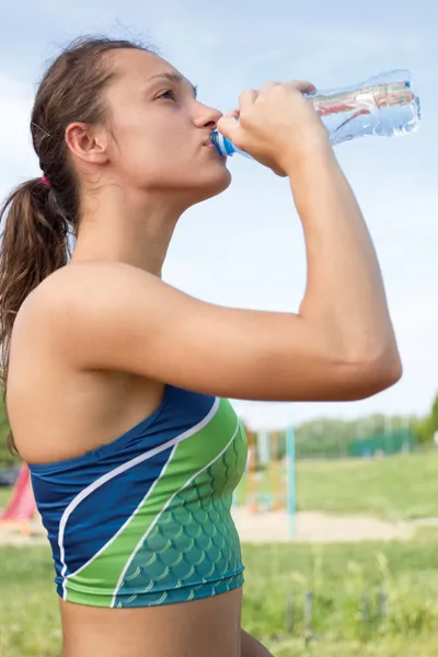 Sportovní žena pitná voda venku na slunečný den — Stock fotografie