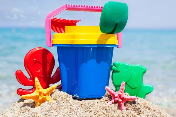 Child's bucket, spade and other toys on tropical beach against b — Stock Photo, Image