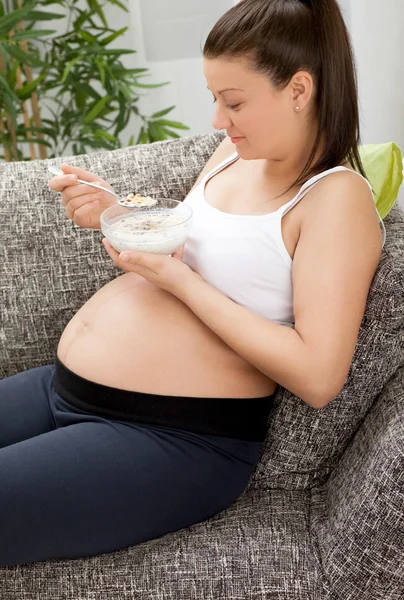 Lachende mooie zwangere vrouw eten granen — Stockfoto