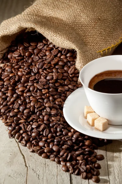 Koffiekopje met jute zak van geroosterde bonen — Stockfoto