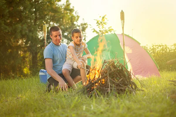 Familia en un viaje de campamento, el padre y el hijo hornear salchicha —  Fotos de Stock