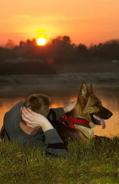 Hombre y pastor alemán en la naturaleza observando la puesta del sol — Foto de Stock