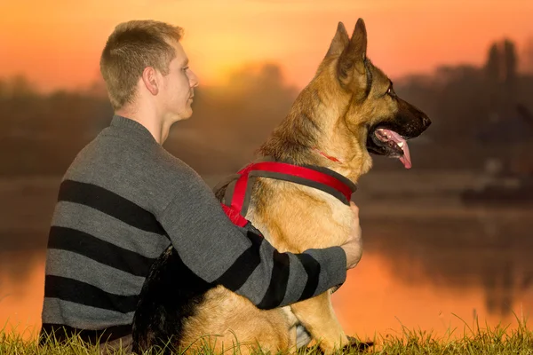 Uomo e pastore tedesco in natura guardando il tramonto — Foto Stock