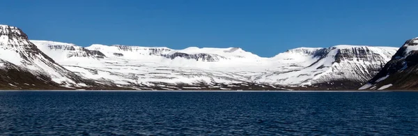 Belas montanhas com picaretas de neve e água azul-turquesa do oceano Atlântico. Westfjords, Islândia. Bandeira horizontal. — Fotografia de Stock