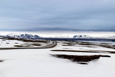 İzlanda 'daki Thingvellir Ulusal Parkı' na kış yolu. Kardaki dağlar ve Thingvallavatn Gölü. Turistik cazibe Altın Çember.