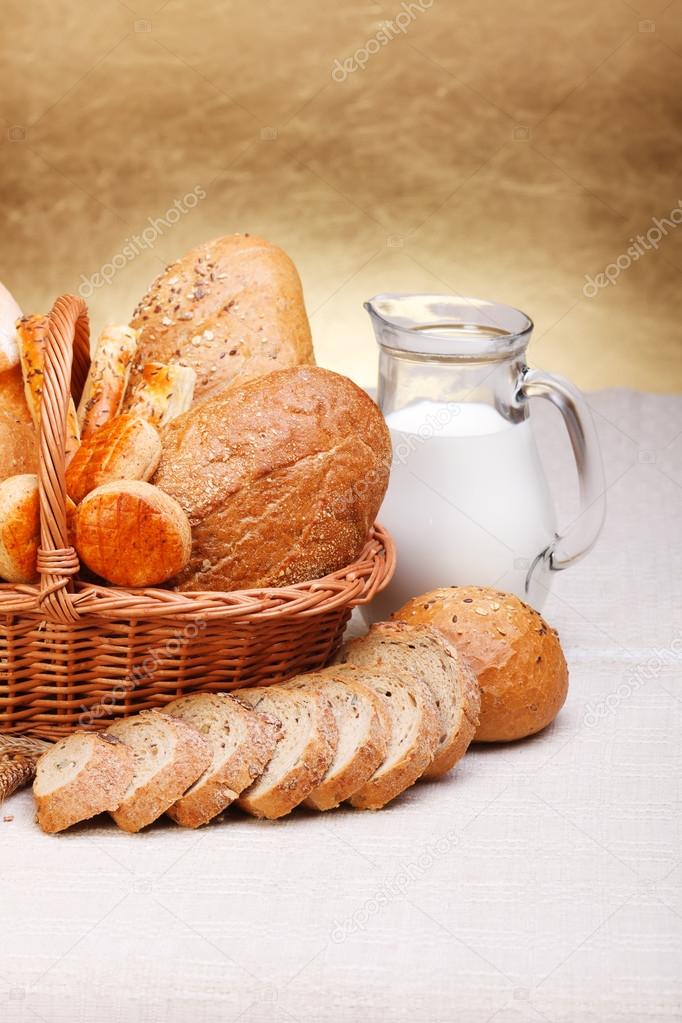 Bread products in basket and jug of milk