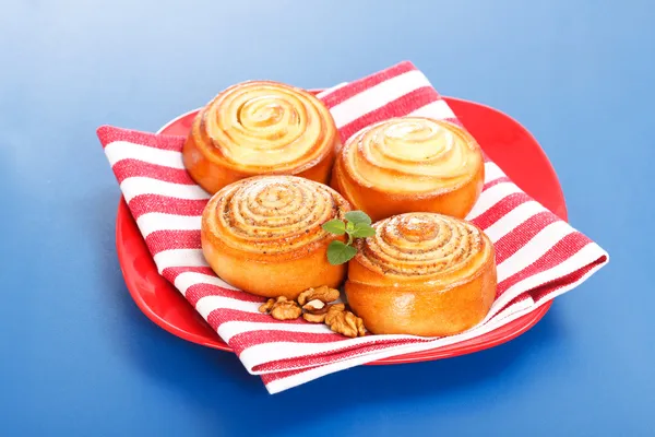 Четыре булочки корицы на красной тарелке — стоковое фото