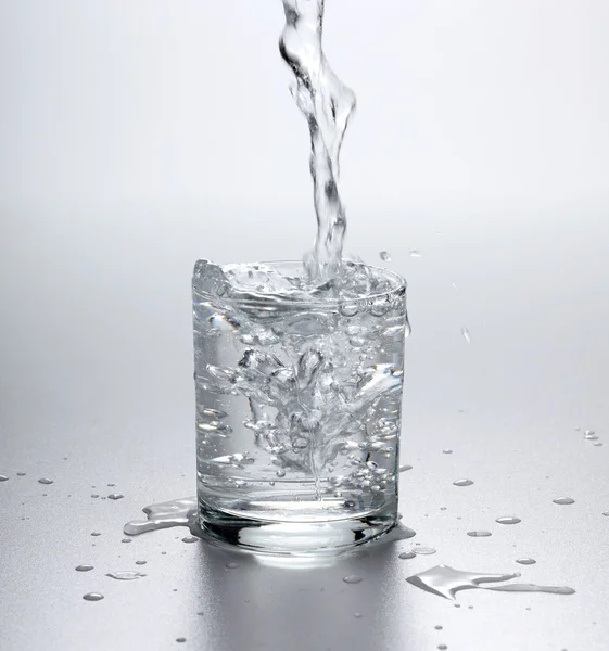 Vatten som rinner in i fullt glas — Stockfoto