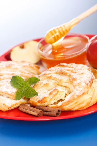 Pasteles de manzana en el plato, miel y trozos de manzana alrededor — Foto de Stock