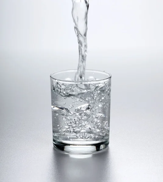 Water flowing into full glass — Stock Photo, Image