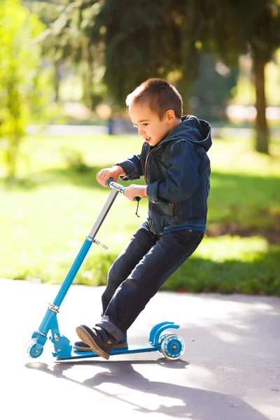 Garçon chevauchant un scooter dans le parc — Photo