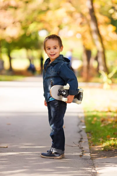 Niño jugando al aire libre con monopatín — Foto de Stock