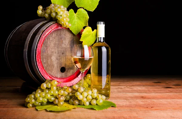 Vino blanco y uvas frente a barrica vieja — Foto de Stock