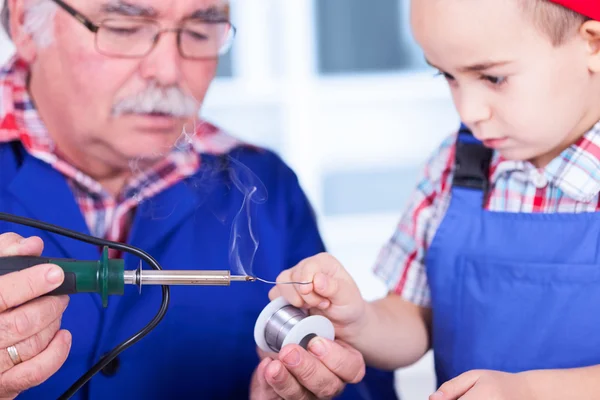 Grandchild touching solder wire to hot soldering iron tip — Stock Photo, Image
