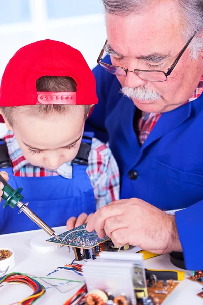 Grandfather teaching grandchild soldering with iron — Stock Photo, Image