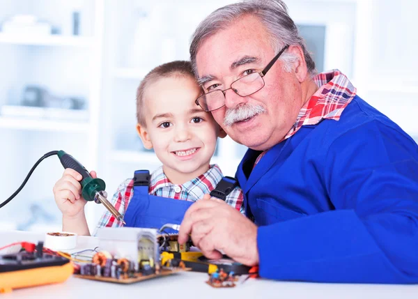 Happy grandfather and grandchild working together in workshop — Stock Photo, Image