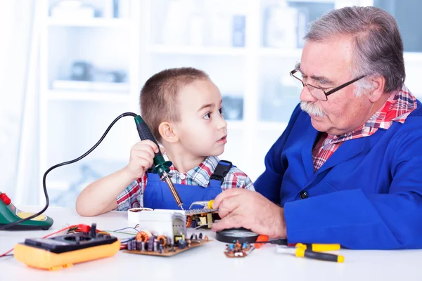 Grandfather teaching grandchild working with soldering iron — Stock Photo, Image