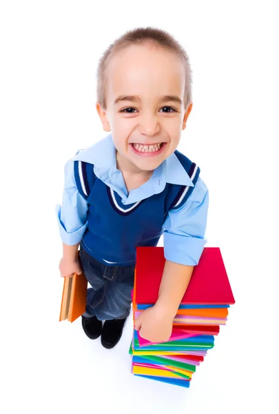 Menino de pé perto de livros coloridos empilhados — Fotografia de Stock