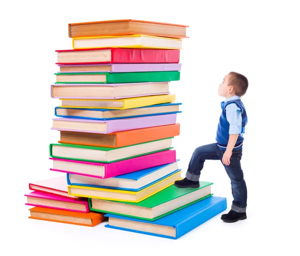 Menino olhando para livros grandes empilhados — Fotografia de Stock