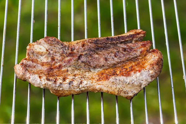 Fried meat slice on barbecue grid — Stock Photo, Image