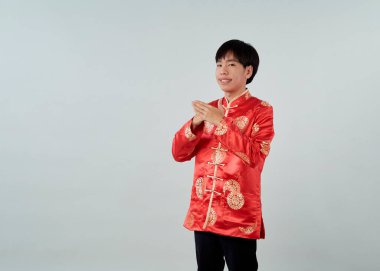 Kırmızı mandalina yakalı genç bir Asyalı stüdyo gri arka planda bir tebrik jesti sergiliyor Mutlu Çin Yeni Yılı