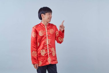 Mutlu Asyalı adam geleneksel oryantal kostüm Çin 'in yeni yıl kavramları için izole edilmiş gri arka plandaki fotokopi alanını işaret ediyor.