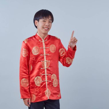 Mutlu Asyalı adam geleneksel oryantal kostüm Çin 'in yeni yıl kavramları için izole edilmiş gri arka plandaki fotokopi alanını işaret ediyor.