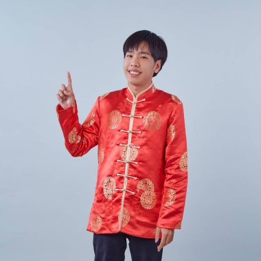 Mutlu Asyalı adam geleneksel oryantal kostüm Çin 'in yeni yıl kavramları için izole edilmiş gri arka plandaki fotokopi alanını işaret ediyor.