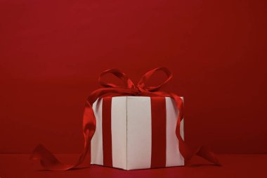 Kırmızı arkaplanda kırmızı kurdeleli hediye kutusu Noel.