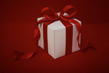 Kırmızı arkaplanda kırmızı kurdeleli hediye kutusu Noel.
