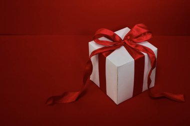 Kırmızı arkaplanda kırmızı kurdeleli hediye kutusu Noel.
