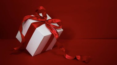 Kırmızı arkaplanda kırmızı kurdeleli hediye kutusu Noel.