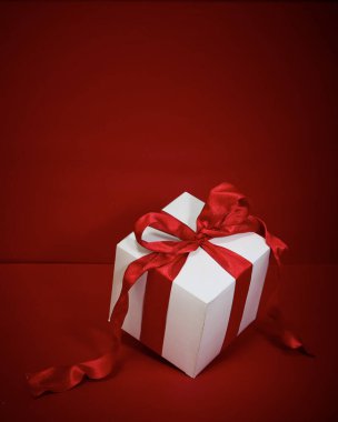 Kırmızı arkaplanda kırmızı kurdeleli hediye kutusu Noel.