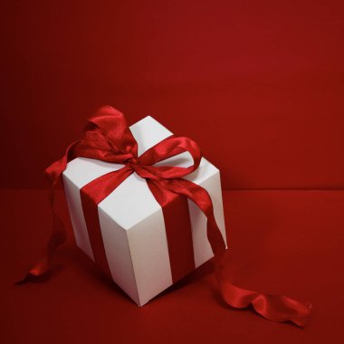 Kırmızı arkaplanda kırmızı kurdeleli hediye kutusu Noel.