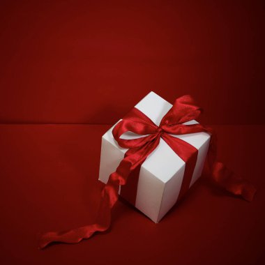 Kırmızı arkaplanda kırmızı kurdeleli hediye kutusu Noel.