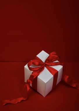 Kırmızı arkaplanda kırmızı kurdeleli hediye kutusu Noel.